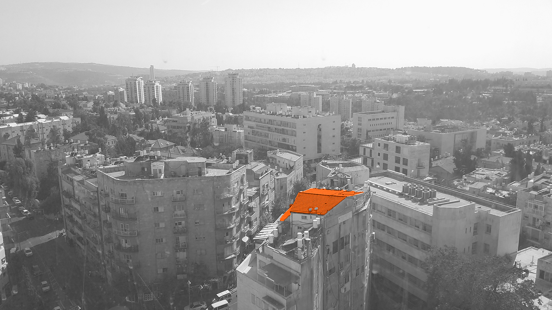 Black-and-white view over the rooftops of Rehavia, Jerusalem, from the City Tower, with one red-tiled roof highlighted in orange