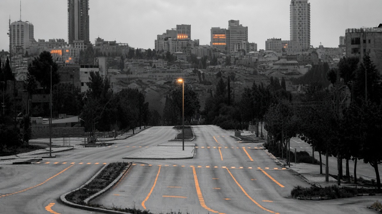 Empty Tel Aviv avenue in black and white; soft orange lane markings and lights as Yom Kippur peace settles