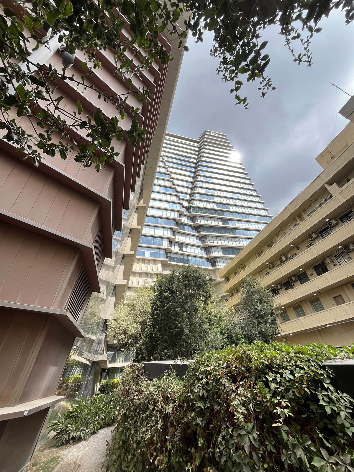 The ToHa tower and its logo above the courtyard greenery, next to the EAST&TLV site